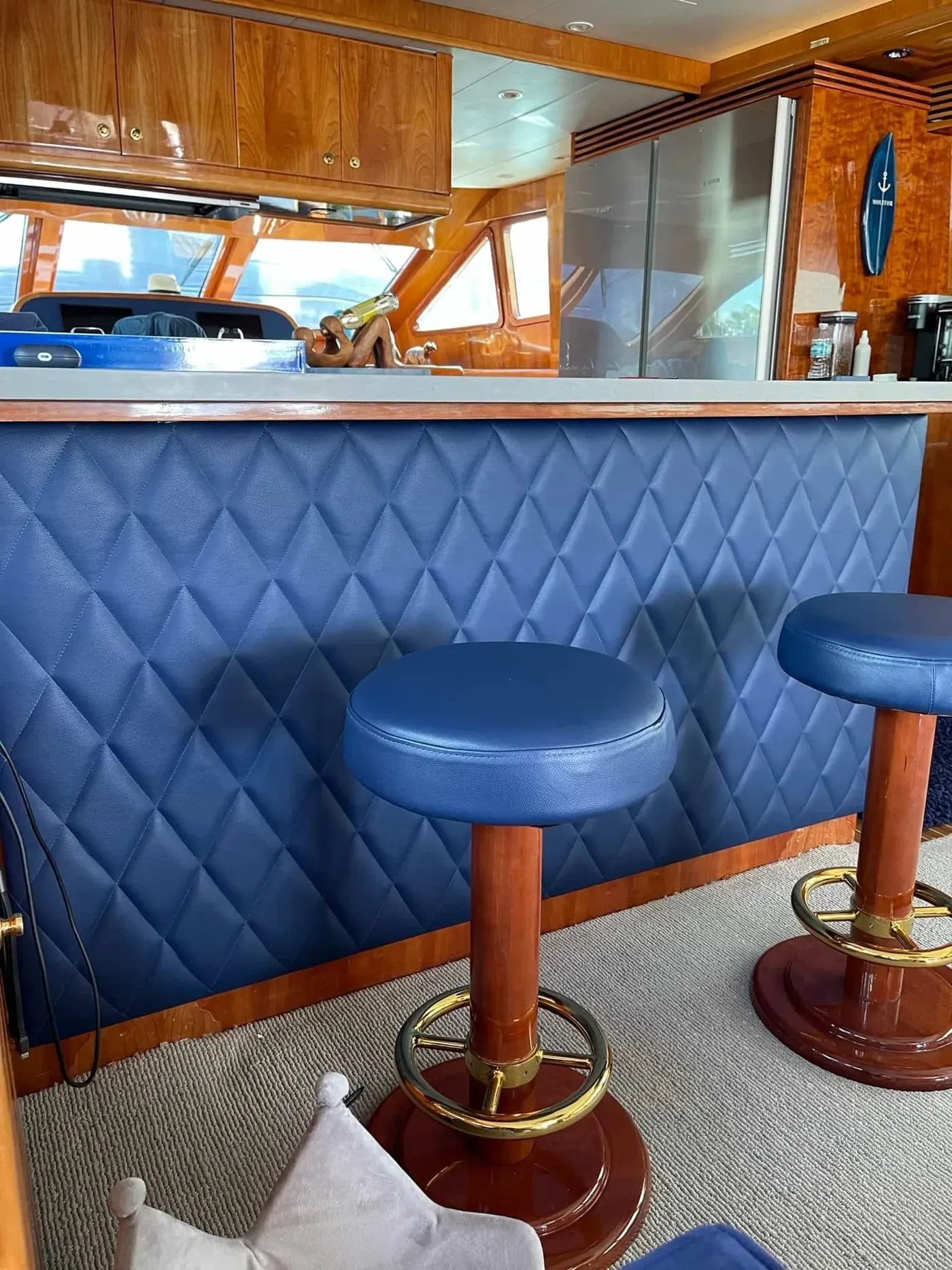 Yacht bar with diamond-stitched blue upholstery and stools
